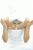 Woman washing her face, splashing water - Asia Images Group
