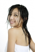 Woman with wet hair, wrapped in a towel, looking over shoulder - Asia Images Group