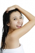 Woman with wet hair, wrapped in a towel, looking over shoulder, hand on head - Asia Images Group