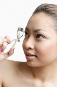 Young woman holding eyelash curler - Asia Images Group