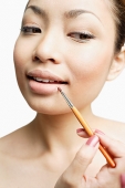 Young woman using lipstick brush, portrait - Asia Images Group