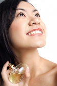 Woman holding perfume bottle, looking up - Asia Images Group
