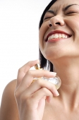 Woman holding perfume bottle, eyes closed, smiling - Asia Images Group