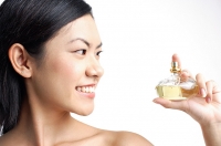 Woman looking at perfume bottle - Asia Images Group