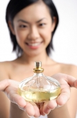Woman holding perfume bottle - Asia Images Group