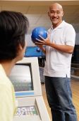 Man standing in bowling ally, holding bowling ball - Asia Images Group