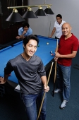 Four men standing around pool table, looking at camera - Asia Images Group