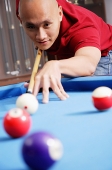 Man holding pool cue, aiming at ball - Asia Images Group