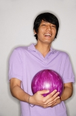 Man carrying bowling ball, looking at camera - Asia Images Group