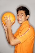 Man holding bowling ball, looking at camera - Asia Images Group