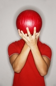Man holding bowling ball in front of his face - Asia Images Group