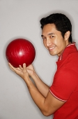 Man holding bowling ball, turning to smile at camera - Asia Images Group