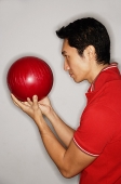 Man holding bowling ball in front of face - Asia Images Group