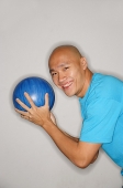 Man holding bowling ball turning to smile at camera, side view - Asia Images Group