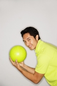 Man holding bowling ball, turning to look at camera - Asia Images Group