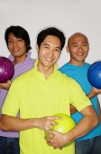 Three men holding bowling balls, smiling at camera - Asia Images Group