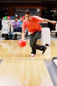 Man bowling, people watching in the background - Asia Images Group