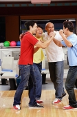 Four guys at a bowling alley, celebrating - Asia Images Group