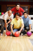 Four men in bowling alley, looking at camera, portrait - Asia Images Group