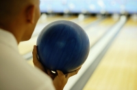 Man holding bowling ball, over the shoulder view - Asia Images Group