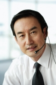 Businessman using headset, looking at camera - Asia Images Group