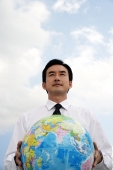 Businessman standing and holding globe - Asia Images Group