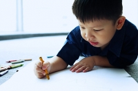 Young boy lying on floor, drawing - Asia Images Group