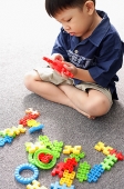 Young boy sitting on floor, playing with building block toys - Asia Images Group