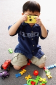Young boy playing with toy camera, holding in front of his face - Asia Images Group