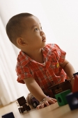 Young boy on floor, playing with toys, looking away - Asia Images Group