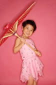 Young girl in pink dress holding umbrella, smiling - Asia Images Group