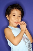 Young girl sucking on lollypop, smiling - Asia Images Group