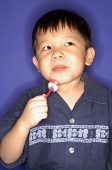 Young boy with lollypop, looking away - Asia Images Group