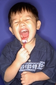 Young boy with lollypop, mouth open, eyes closed - Asia Images Group