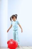 Girl standing, looking at balloons on the floor - Asia Images Group
