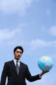 Businessman holding globe, looking at camera - Asia Images Group