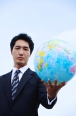 Businessman holding globe towards camera - Asia Images Group