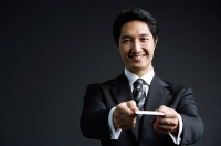 Businessman, looking at camera, offering business card, smiling - Asia Images Group
