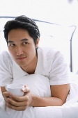 Man on bed, holding cup - Asia Images Group