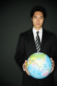 Businessman standing, holding globe in two hands - Asia Images Group