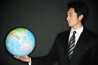 Businessman holding globe in one hand - Asia Images Group