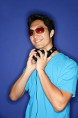 Man wearing sunglasses, headphones around his neck - Asia Images Group