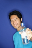 Man holding bottle of water towards camera - Asia Images Group