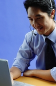 Man wearing headset, using laptop - Asia Images Group