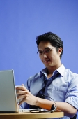 Man sitting in front of laptop, holding mug - Asia Images Group