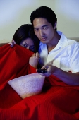 Couple watching TV, woman hiding under blanket - Asia Images Group