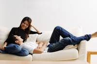 Couple on sofa, man lying on womans lap - Asia Images Group