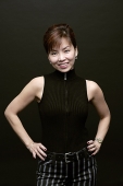 Woman standing, hands on hips, smiling at camera - Asia Images Group