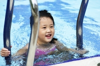 Girl swimming in pool, climbing ladder - Asia Images Group
