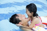 Father and daughter in swimming pool, daughter with float - Asia Images Group